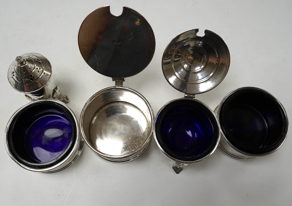 A George V matched silver three piece condiment set, London, 1931(2) and 1933, together with two other silver condiments. Condition - poor to fair